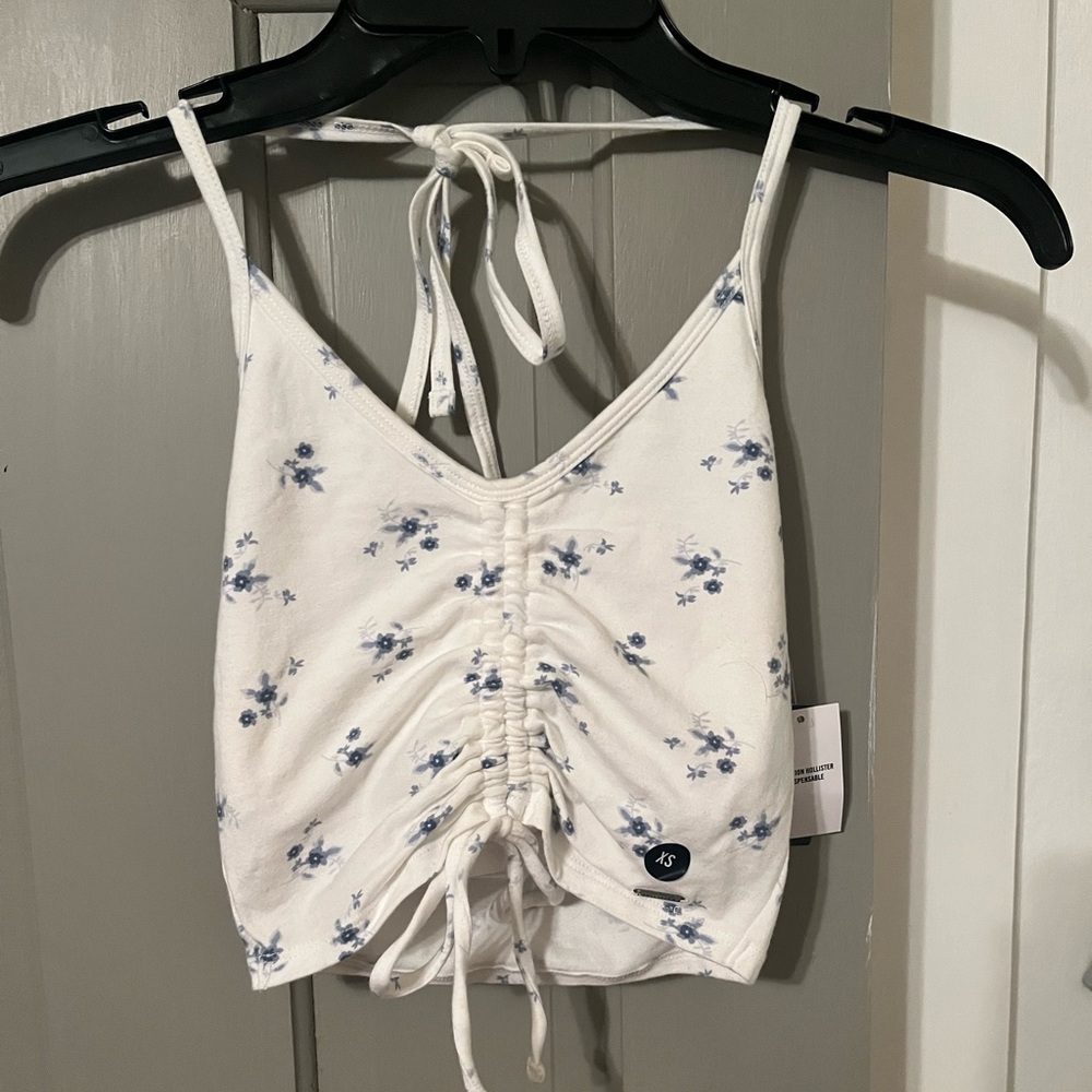 Hollister white halter top with blue flowers and rouching in the front.